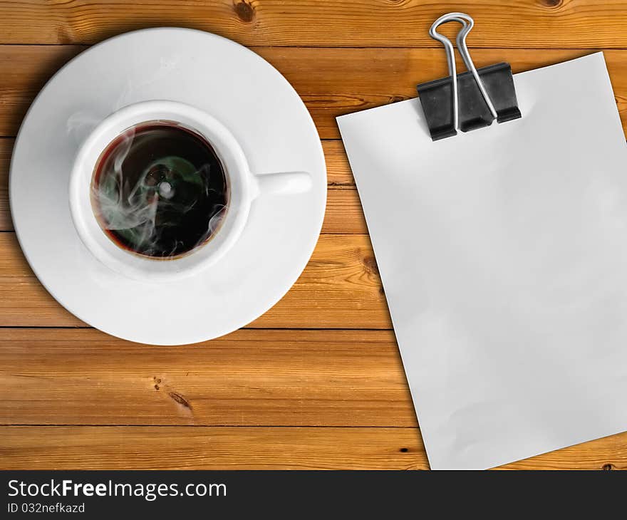 White cup of hot coffee and white paper on wood table