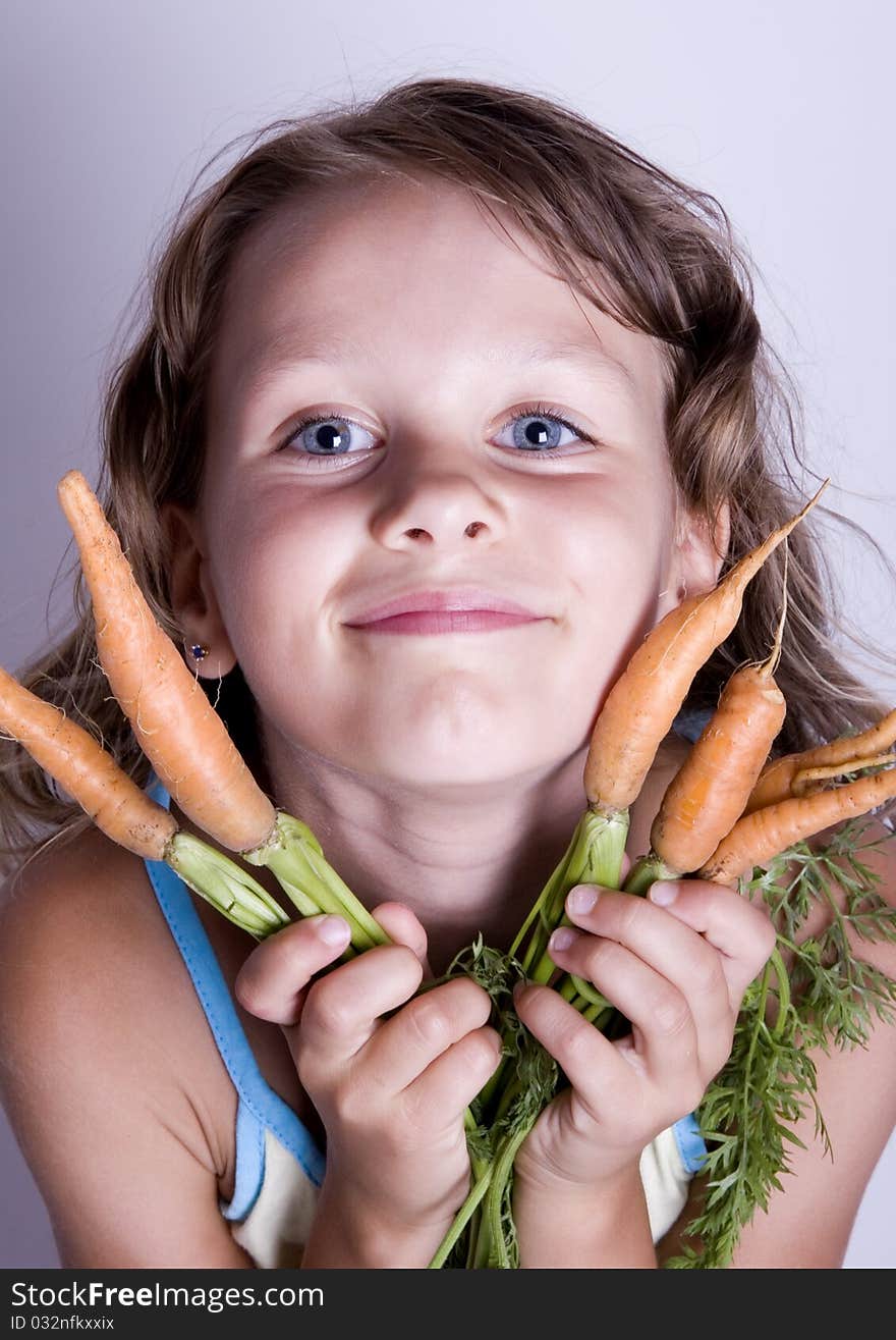 A little girl holding in her hand a beautiful carrots. A little girl holding in her hand a beautiful carrots