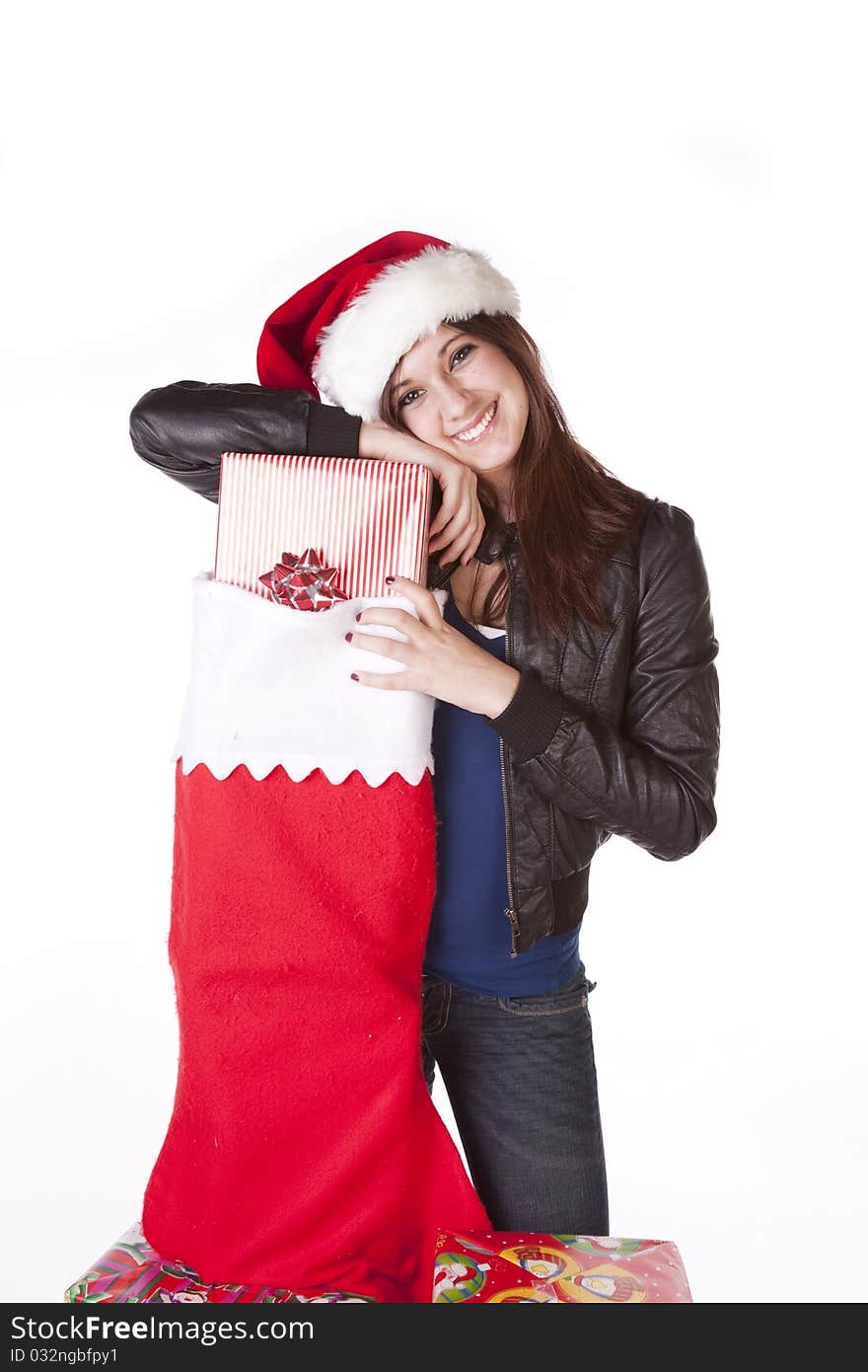 A woman in her Santa hat on with a big smile on her face standing next to a big stocking with presents in it. A woman in her Santa hat on with a big smile on her face standing next to a big stocking with presents in it.