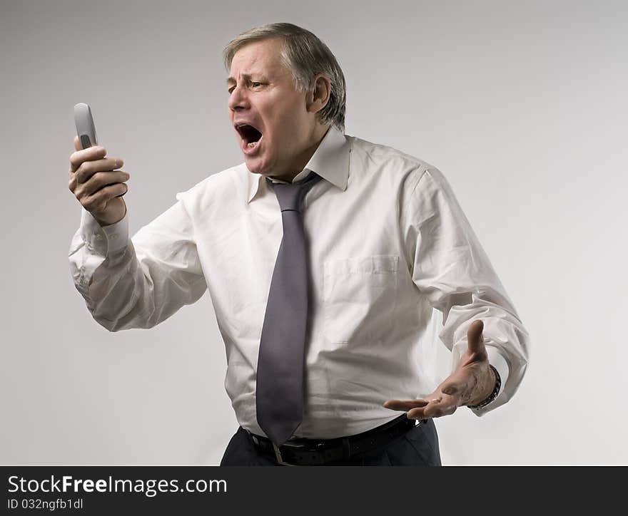 Senior businessman screaming at telephone. Senior businessman screaming at telephone