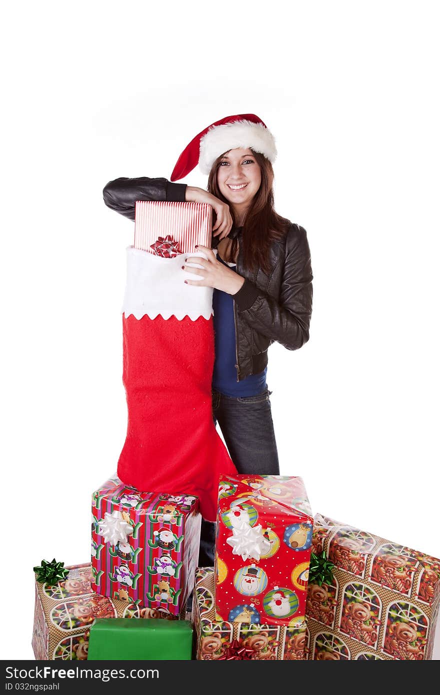 A woman in her Santa hat on with a big smile on her face standing next to a big stocking with presents in it. A woman in her Santa hat on with a big smile on her face standing next to a big stocking with presents in it.