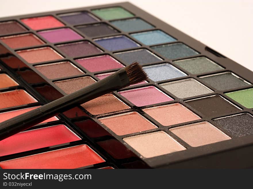 A close-up of a makeup palette with a cosmetic brush.