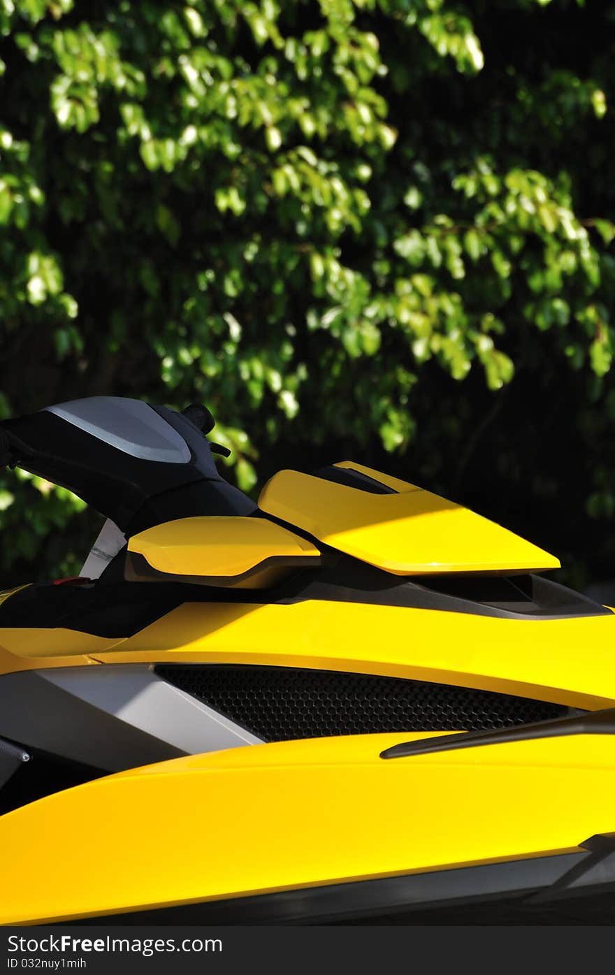 Part of a motor boat body in yellow color, under green tree background, shown as water sport or holiday and entertainment. Part of a motor boat body in yellow color, under green tree background, shown as water sport or holiday and entertainment.