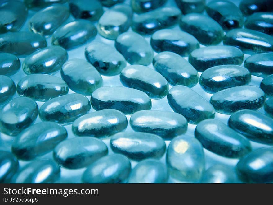 Heap of blue bright glass pebble stones on a turquoise background. Heap of blue bright glass pebble stones on a turquoise background