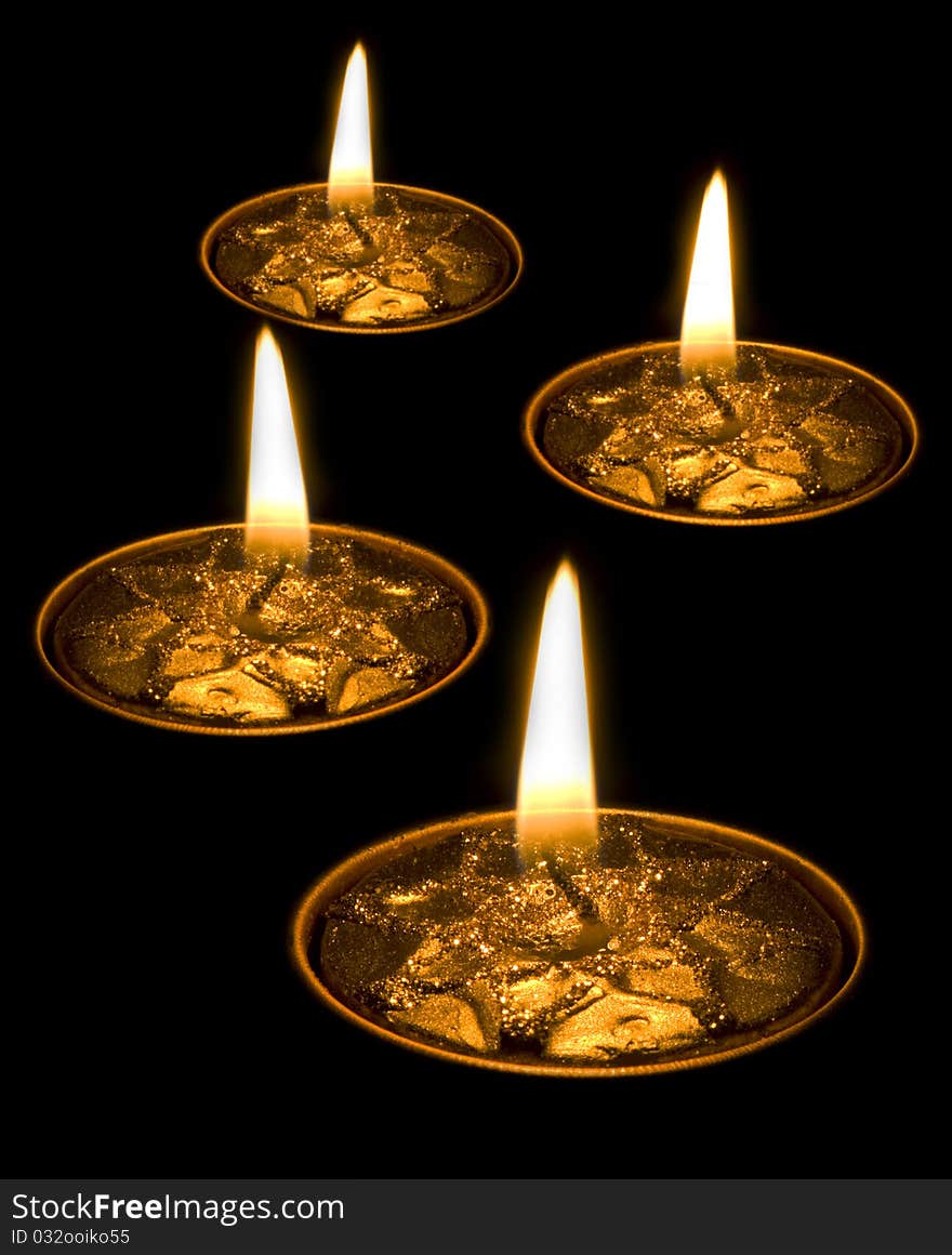 Four burning yellow candles isolated on black background