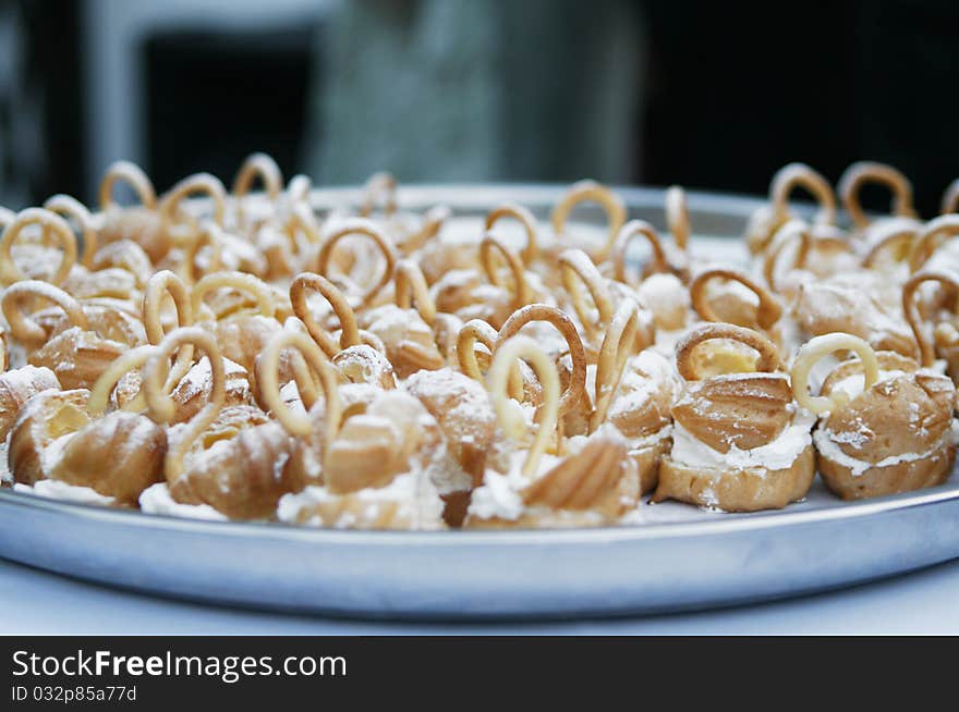 Small delicious wedding cakes with sugar powder on plate.