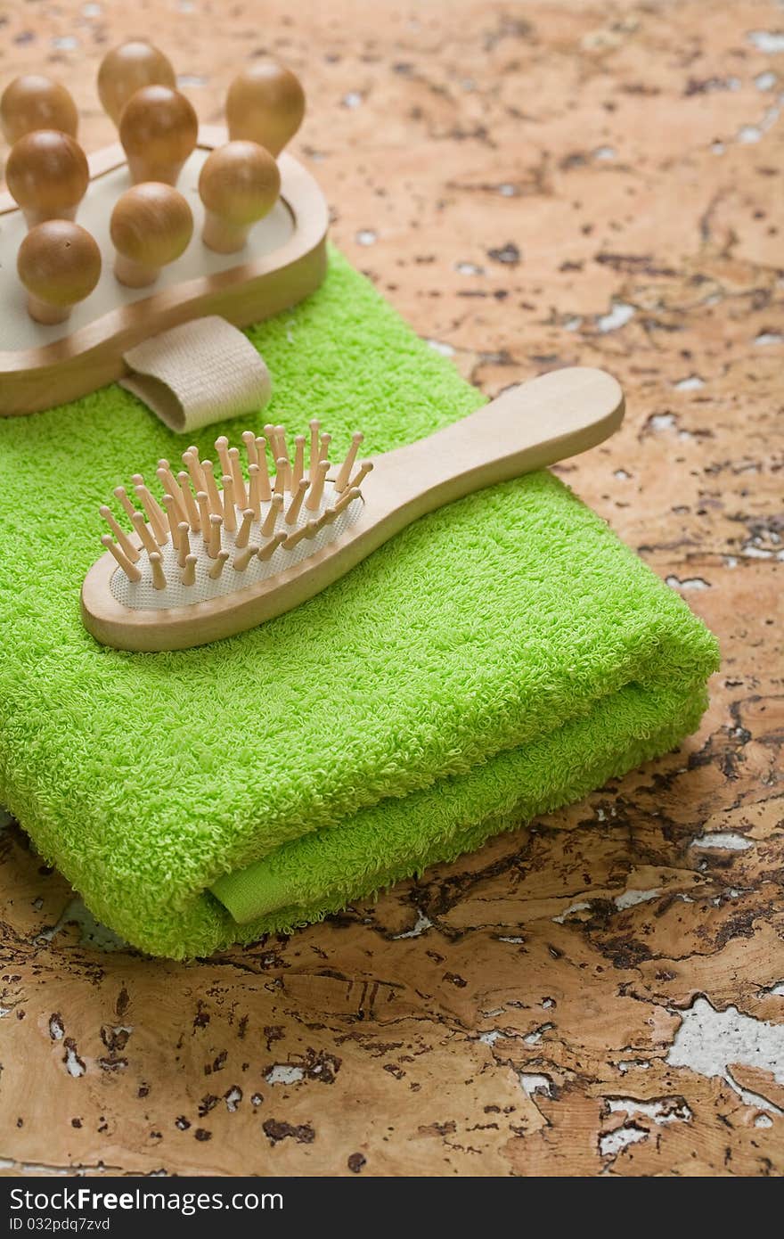 Massager and hairbrush on green towel