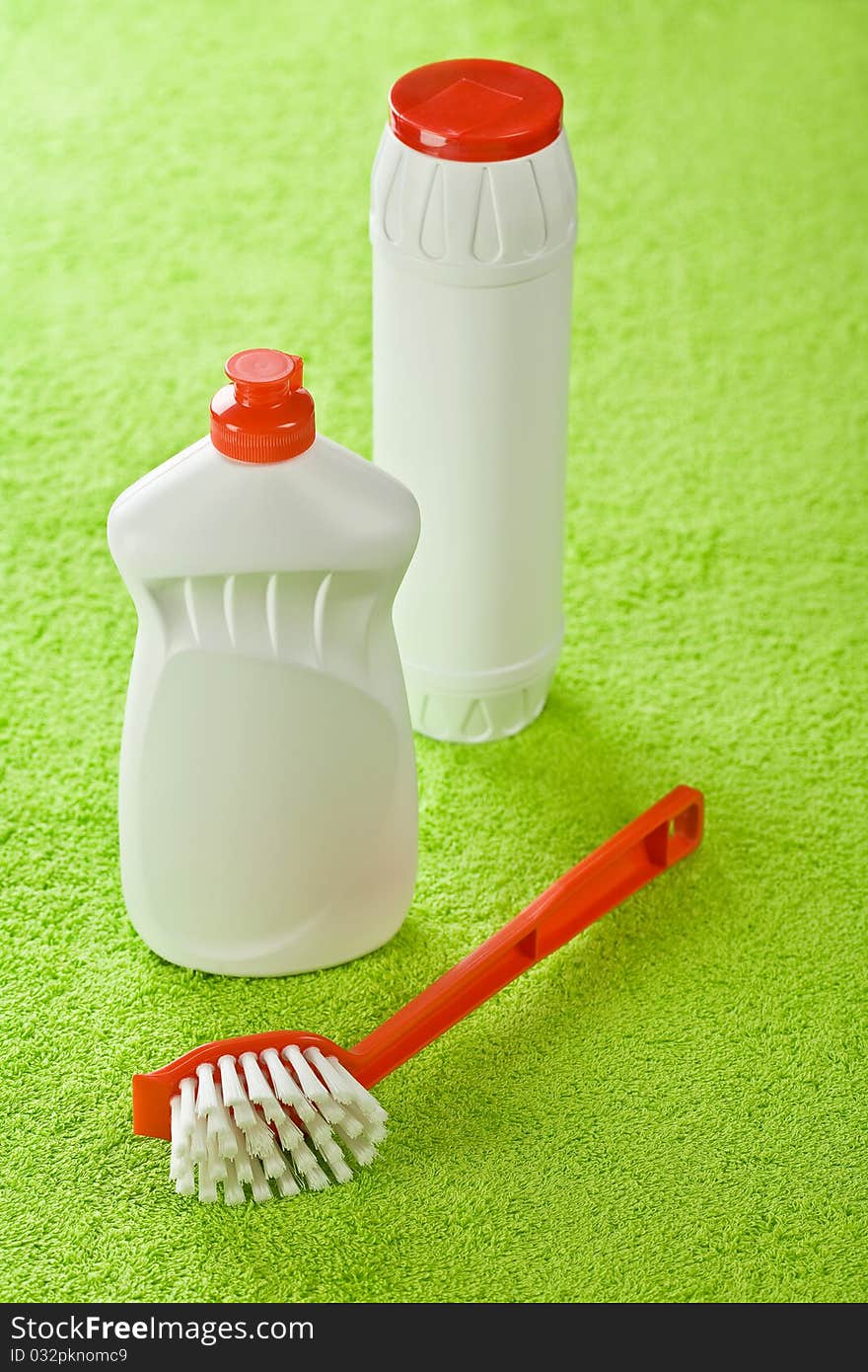 Brush and white bottles on green background of green towel