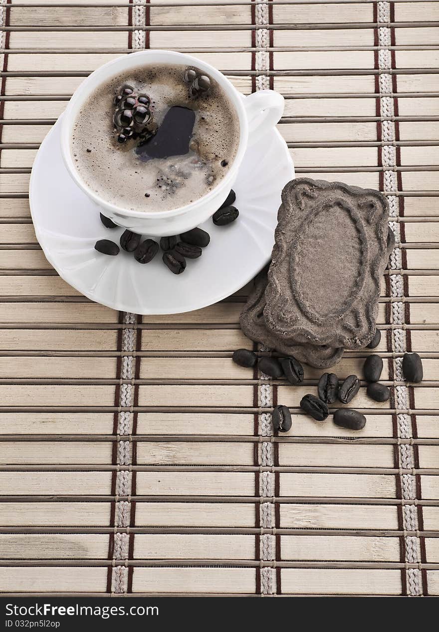 Composition of coffee mug with beans and cookie on matt