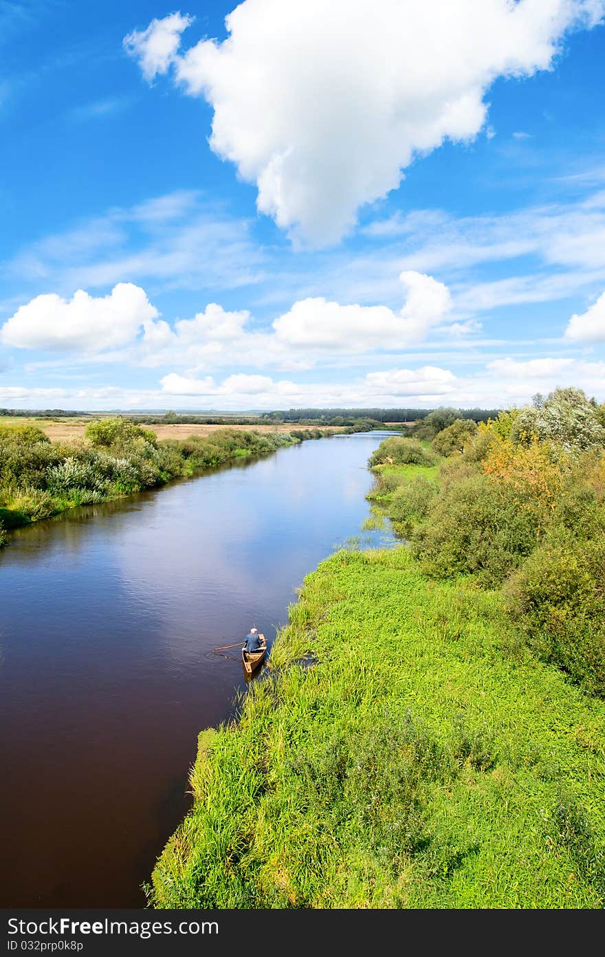 Scenery. Blue river, cloud sky, green shores and small boat. Scenery. Blue river, cloud sky, green shores and small boat.