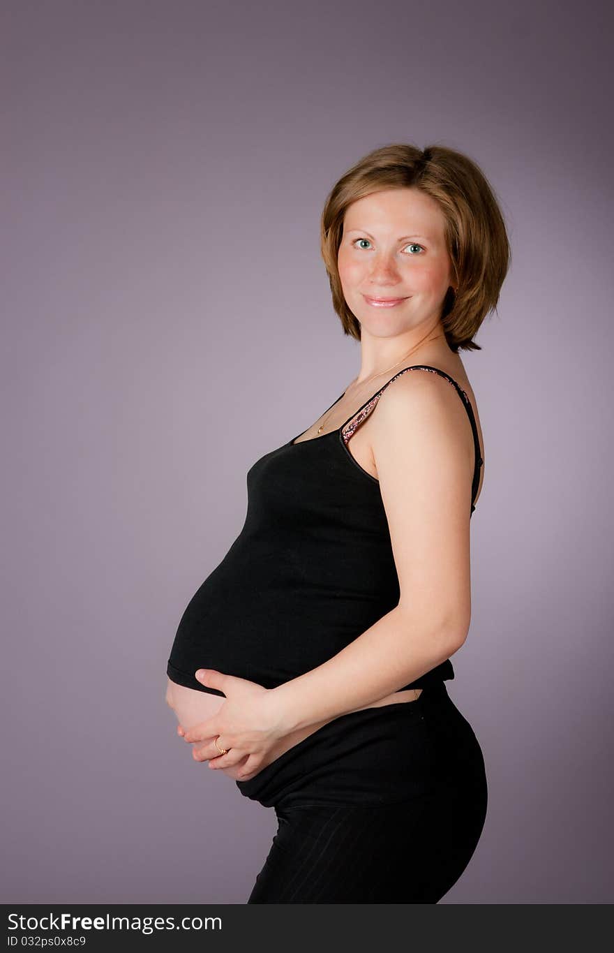 Beautiful pregnant woman staing on grey background