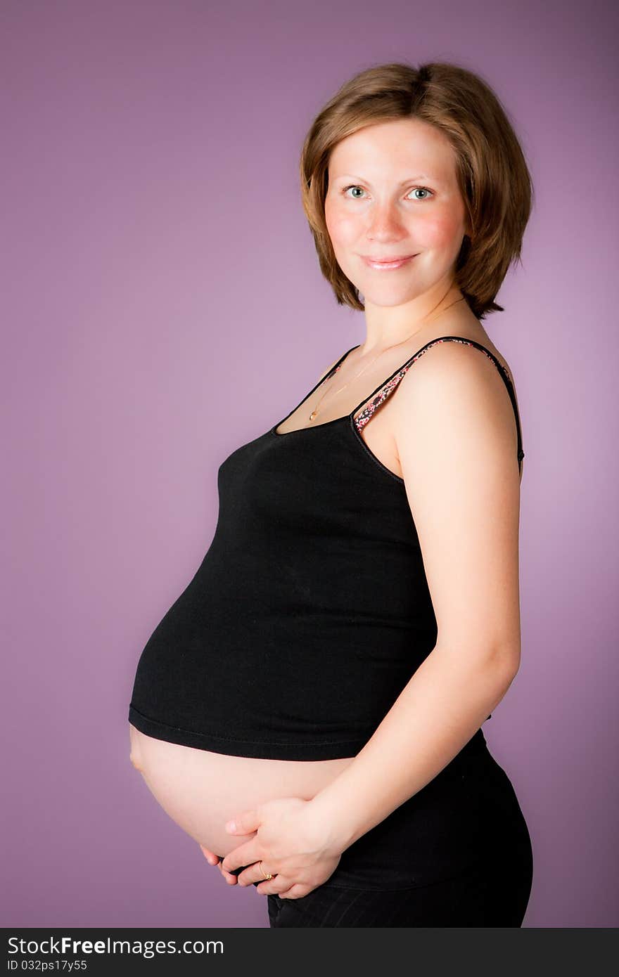 Beautiful pregnant woman staing on purple background