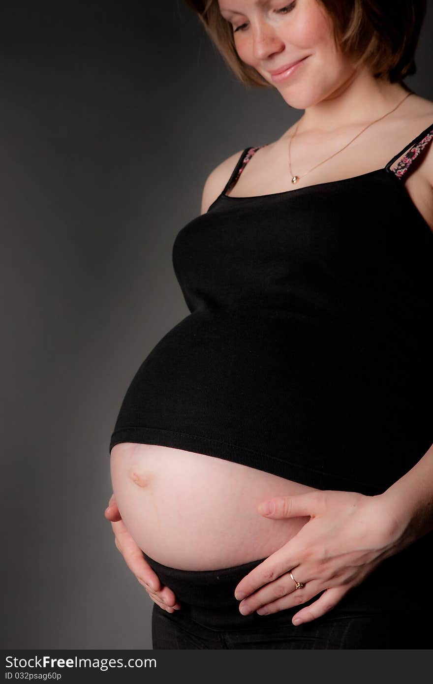 Beautiful pregnant woman staing on grey background