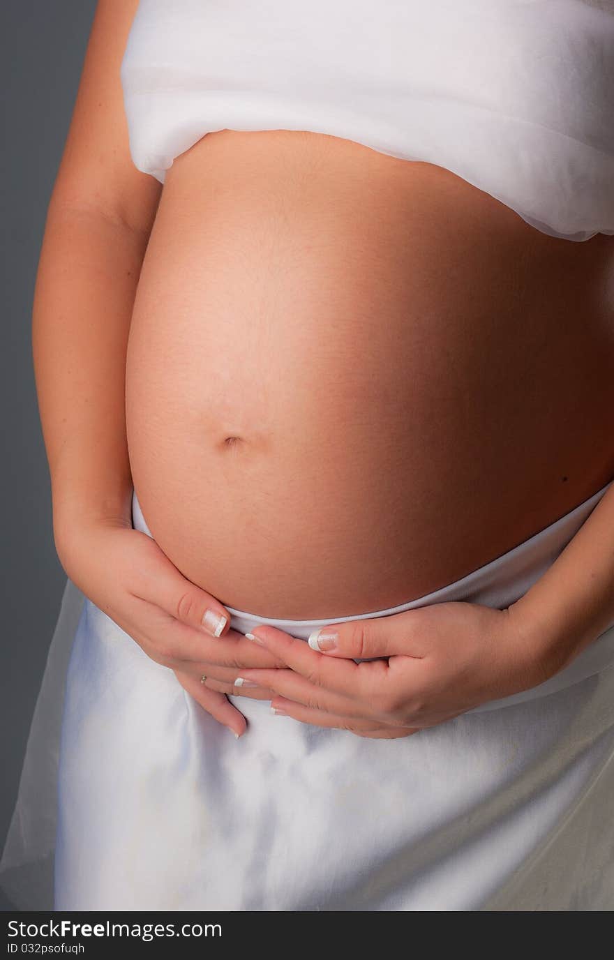 Pregnant woman staing on grey background, close up. Pregnant woman staing on grey background, close up