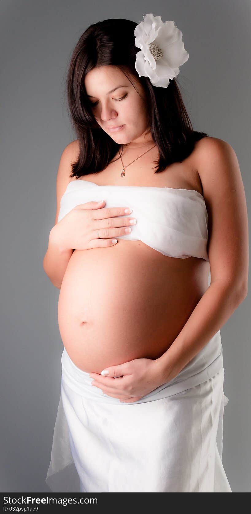 Beautiful pregnant woman staing on grey background, close up