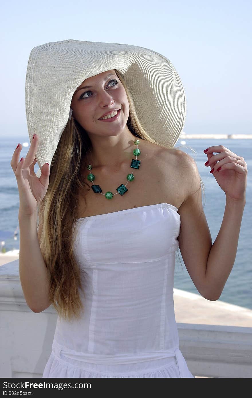 Happy blonde in a hat over sea