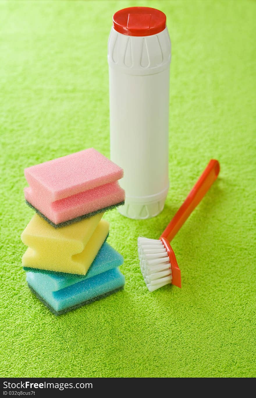 Brush bottle and sponges on green towel