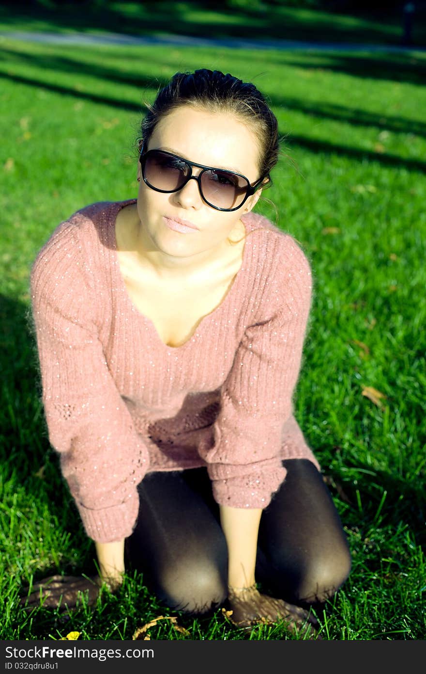 Attractive young woman sitting on green grass