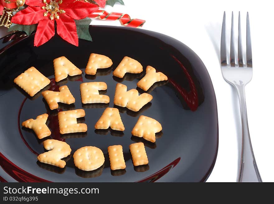 Black plate with character shaped cookies, fork and new year decoration isolated on white. Black plate with character shaped cookies, fork and new year decoration isolated on white