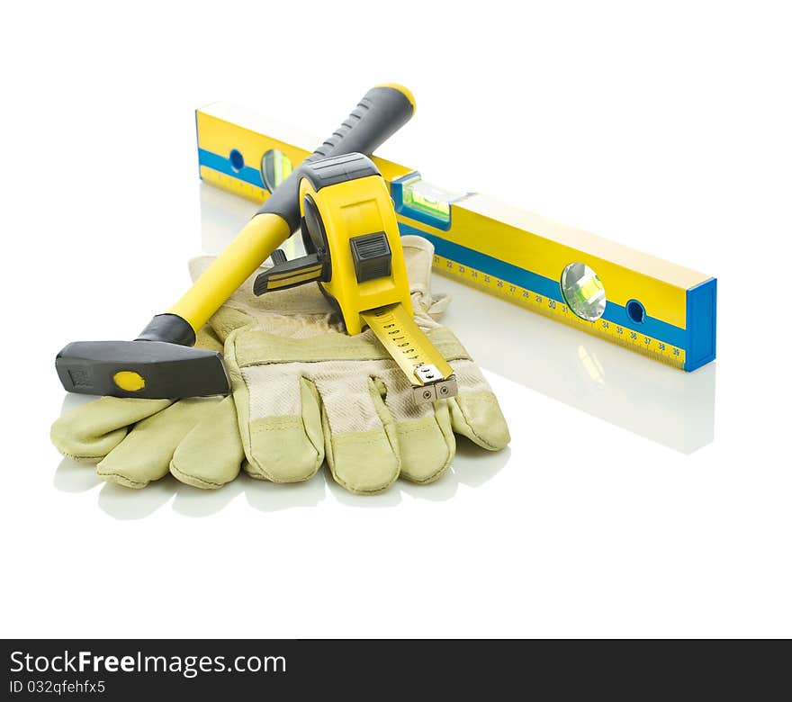 Level, tapeline, hammer and gloves isolated on white background