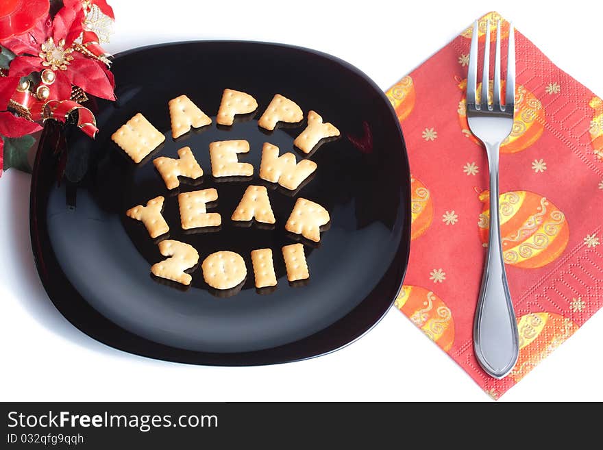 Black plate with character shaped cookies, fork and christmas decoration isolated on white. Black plate with character shaped cookies, fork and christmas decoration isolated on white