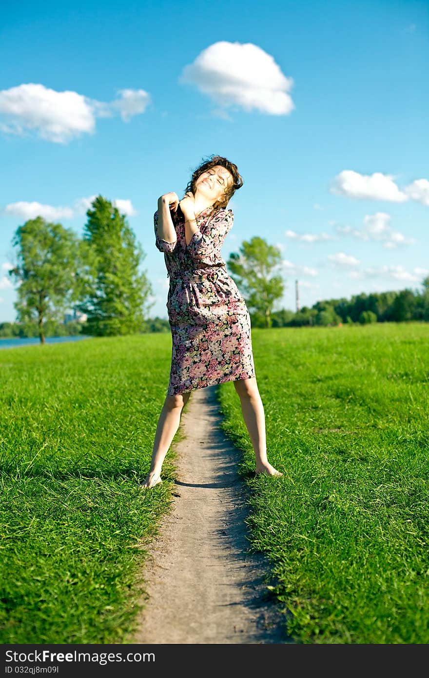 Young woman on meadow with green grass and blue sky