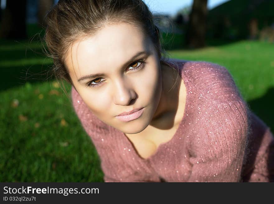 A beautiful young brunette  sits on  green lawn