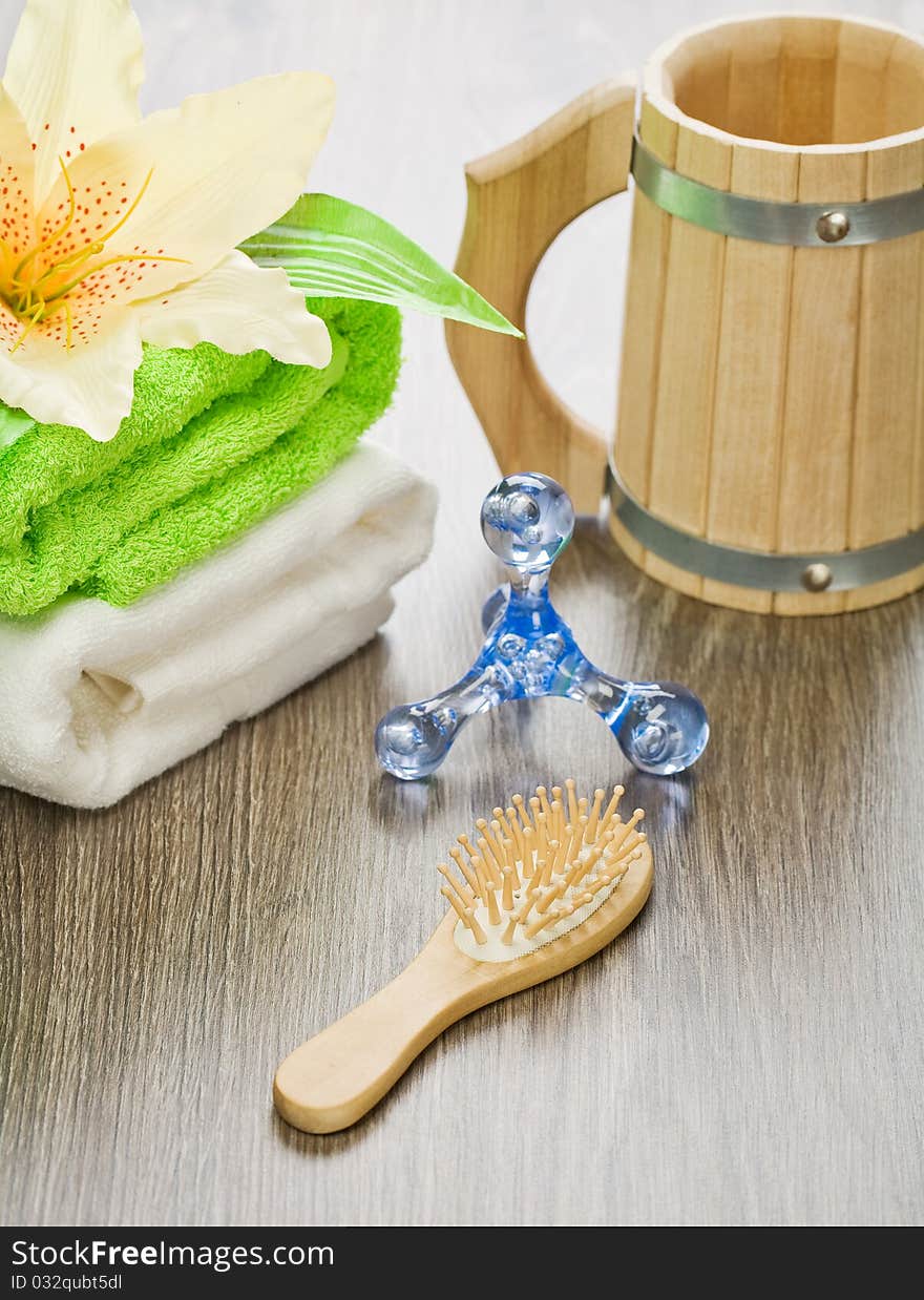 Set of accessories for bathing on wooden background. wooden mug wooden hairbrush plastical massager cooton towels