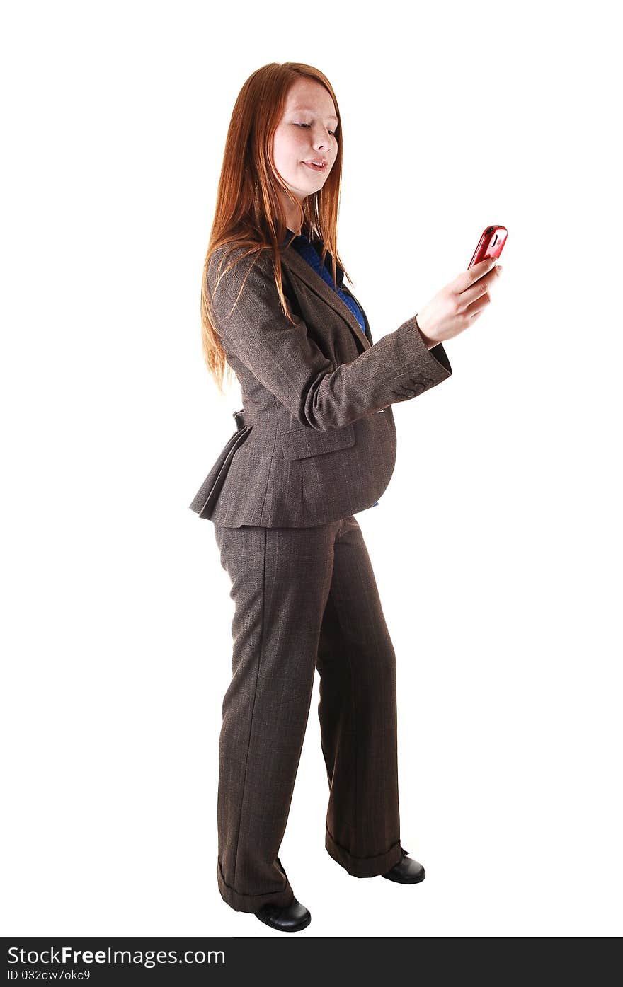 A business woman in a brown suit standing in profile in the studio,
with her long red hair and dialing on her cell phone for white background. A business woman in a brown suit standing in profile in the studio,
with her long red hair and dialing on her cell phone for white background.