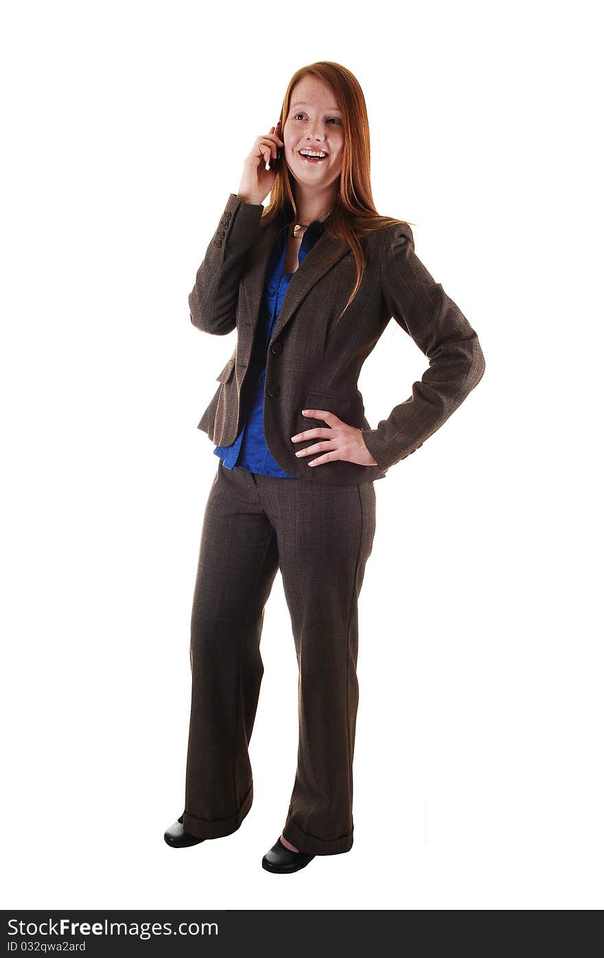 A business woman in a brown suit standing in profile in the studio, with her long red hair and talking on her cell phone for white background. A business woman in a brown suit standing in profile in the studio, with her long red hair and talking on her cell phone for white background.