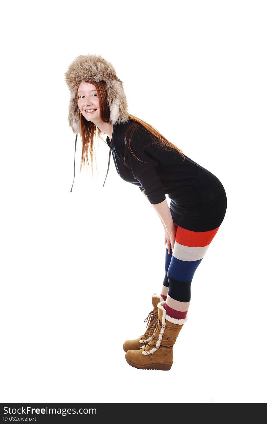 A pretty woman with long red hair in colorful tights, a black sweater and a fur hat and brown boots smiling for a portrait for white background. A pretty woman with long red hair in colorful tights, a black sweater and a fur hat and brown boots smiling for a portrait for white background.