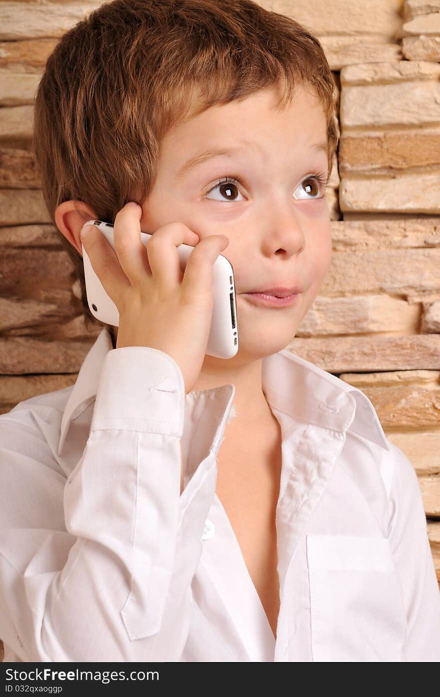 Cute boy in the white shirt talking on the phone. Cute boy in the white shirt talking on the phone