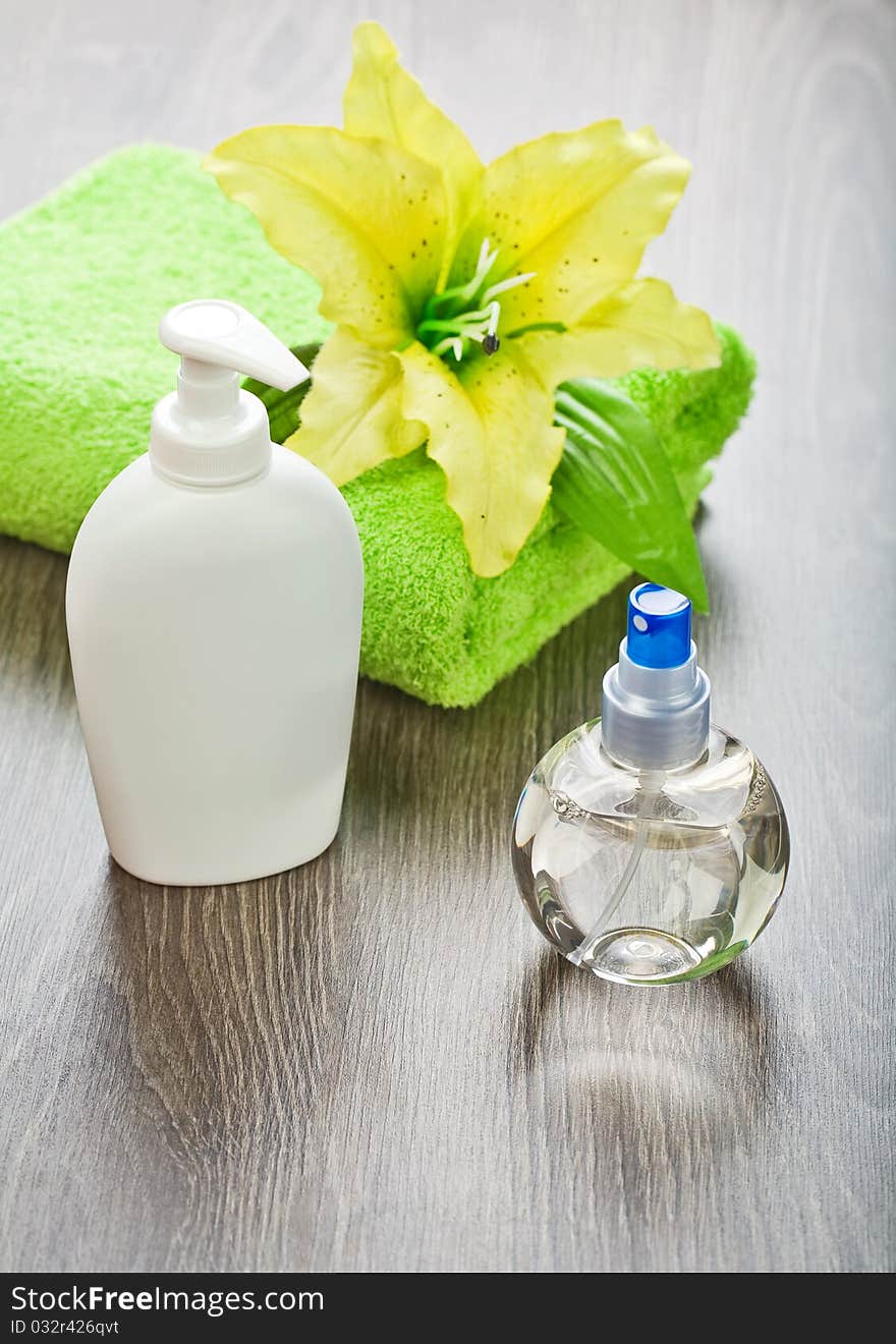 Composition of toilet articles
towel with flower  and bottles on wooden background