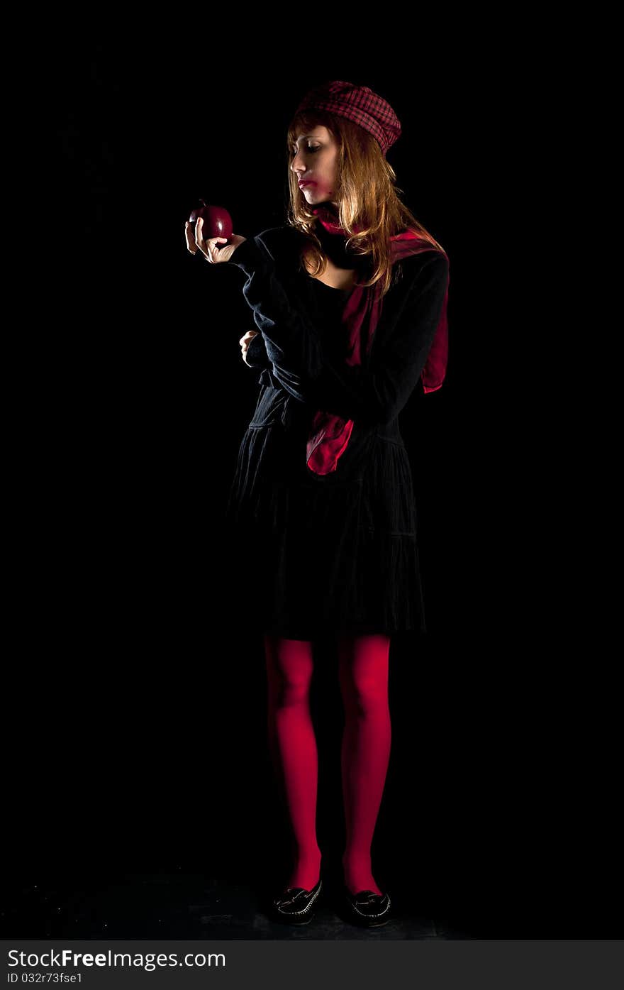 Girl with red socks hat scarf and apple on black background