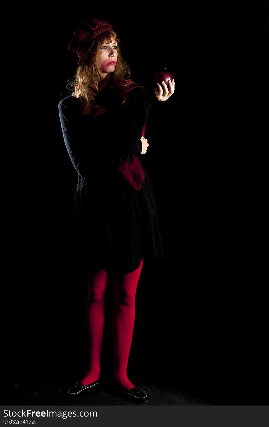 Girl with red socks hat scarf and apple on black background