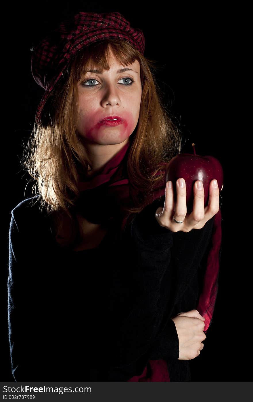 Girl with red socks hat scarf and apple on black background