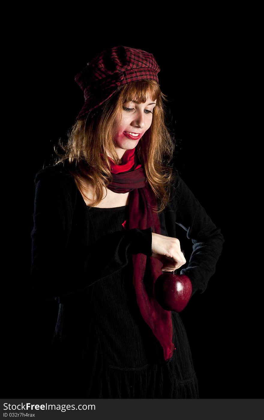 Girl with red socks hat scarf and apple on black background