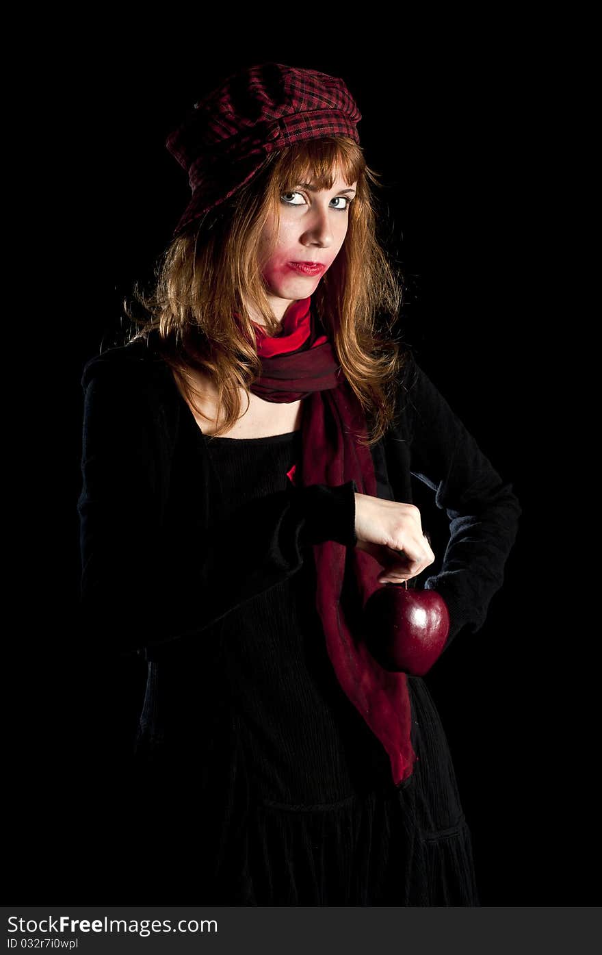 Girl with red socks hat scarf and apple on black background