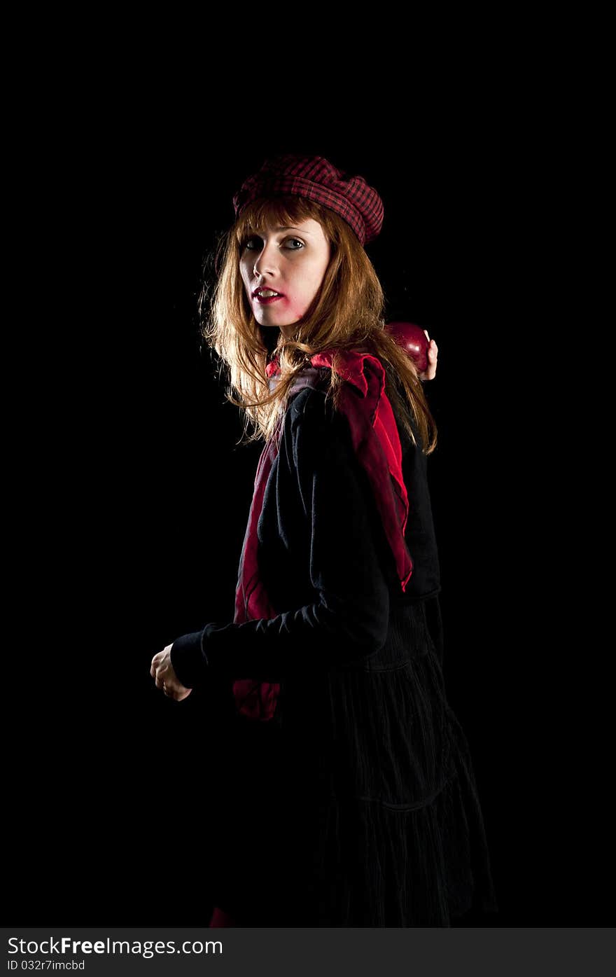 Girl with red socks hat scarf and apple on black background