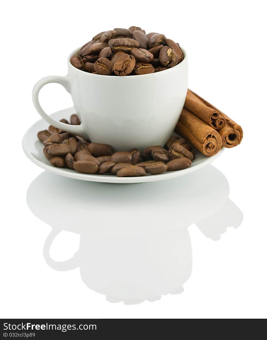 Cup with coffee beans and cinnamon sticks isolated on white background with reflection on white blurry background