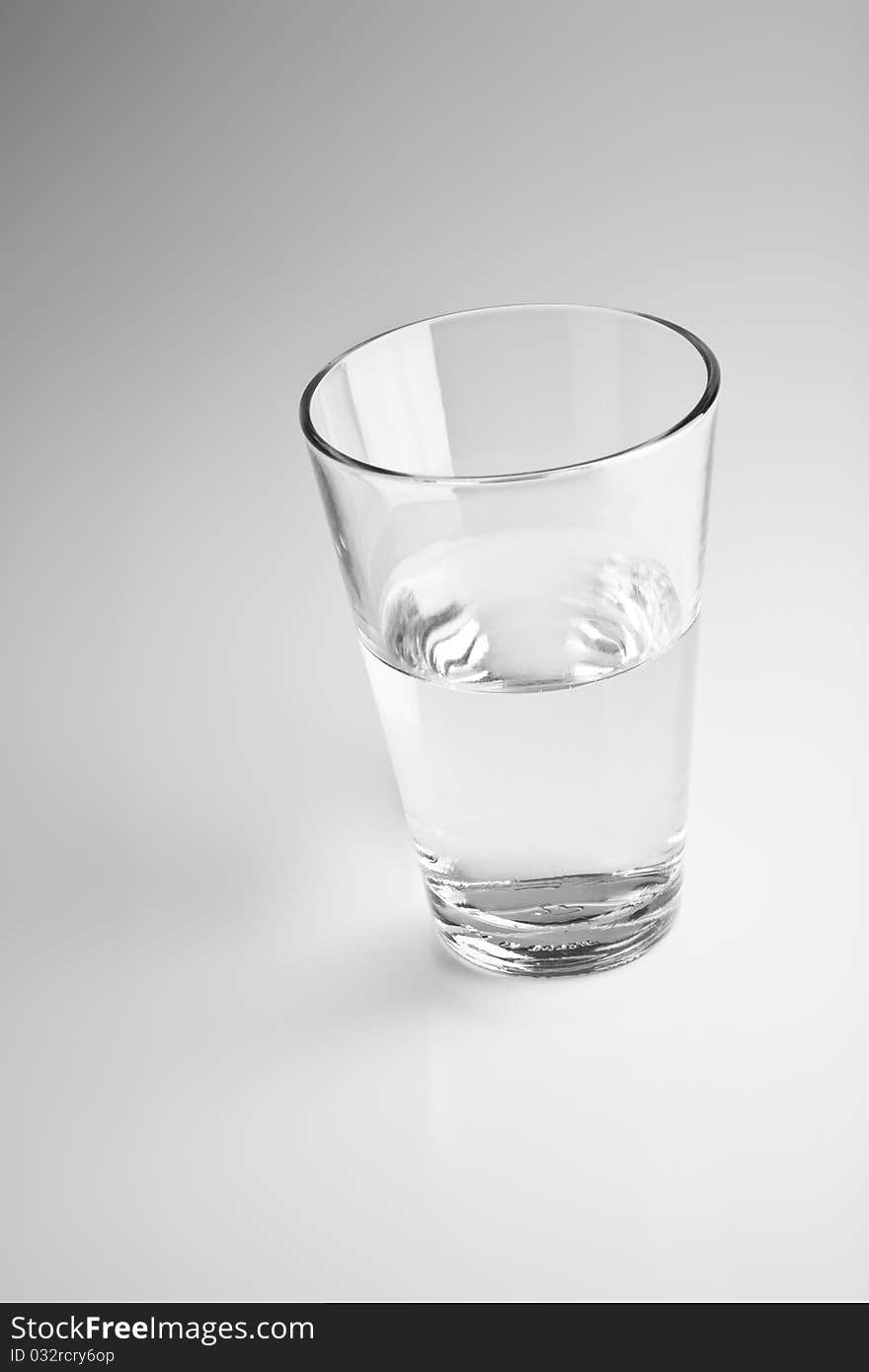 One glass with water on a blurry gray background. One glass with water on a blurry gray background