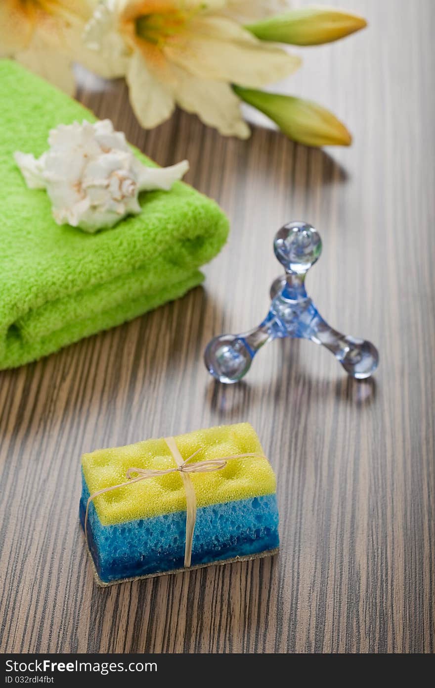 Objects for bathing plastical blue massager green cotton towel hanmade soap combination with yellow sponge flower and cockle shell all its on wooden background. Objects for bathing plastical blue massager green cotton towel hanmade soap combination with yellow sponge flower and cockle shell all its on wooden background