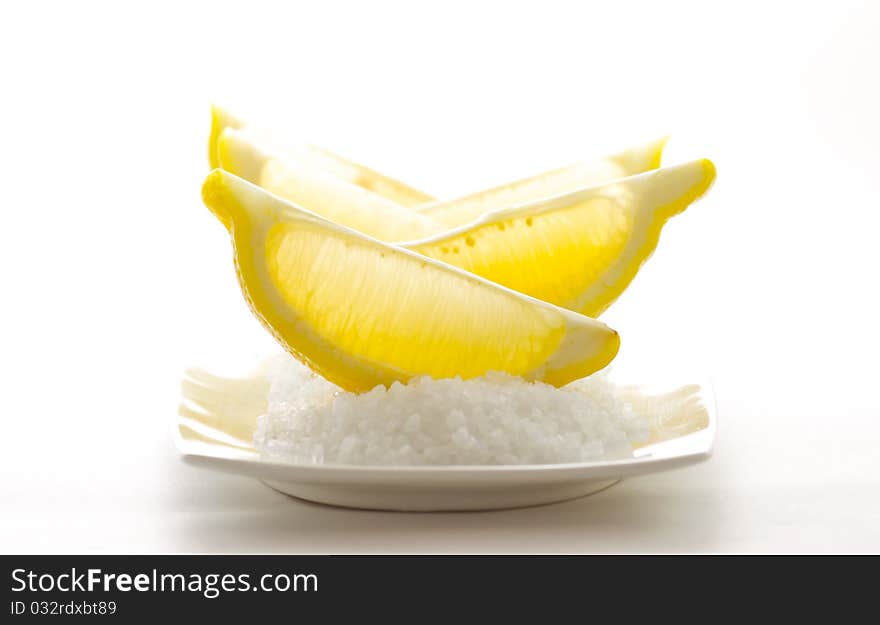 Sliced sour lemons on a bed of sweet coarse sugar, isolated on white background.