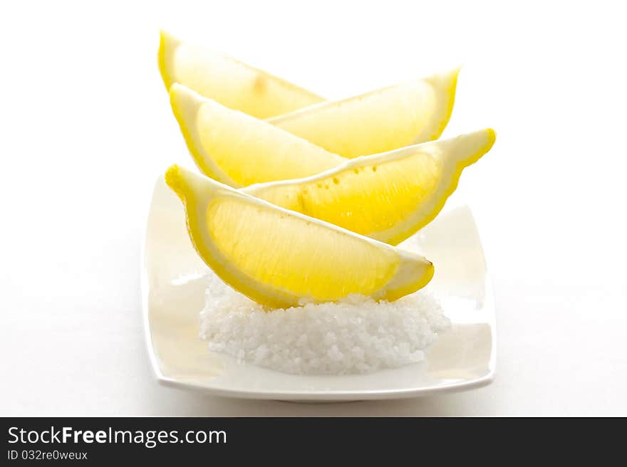 Sliced sour lemons on a bed of sweet coarse sugar, isolated on white background.