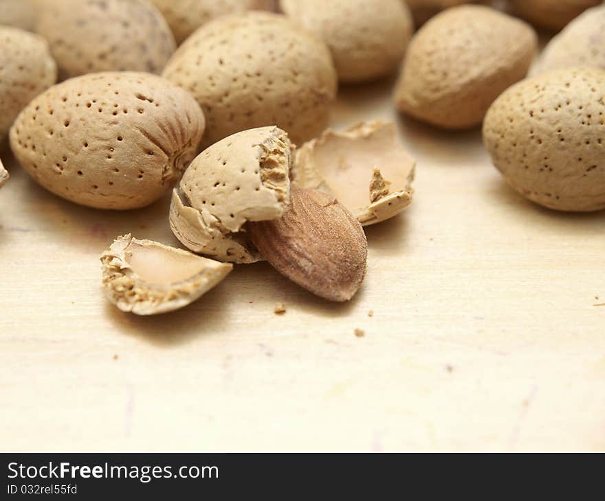 Some almonds on a table, shelled and one unshelled