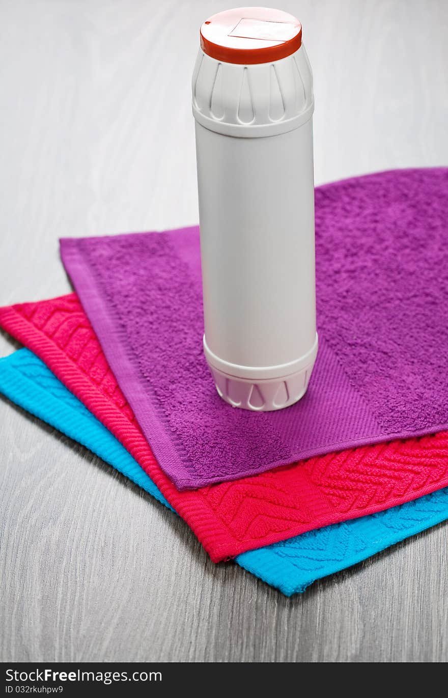 Three towels with bottle on wooden background