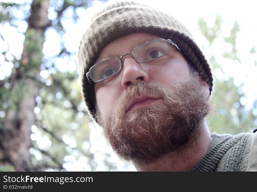 A hunting guide surveys a forest for elk while wearing glasses, a green beanie and a sweater. A hunting guide surveys a forest for elk while wearing glasses, a green beanie and a sweater.