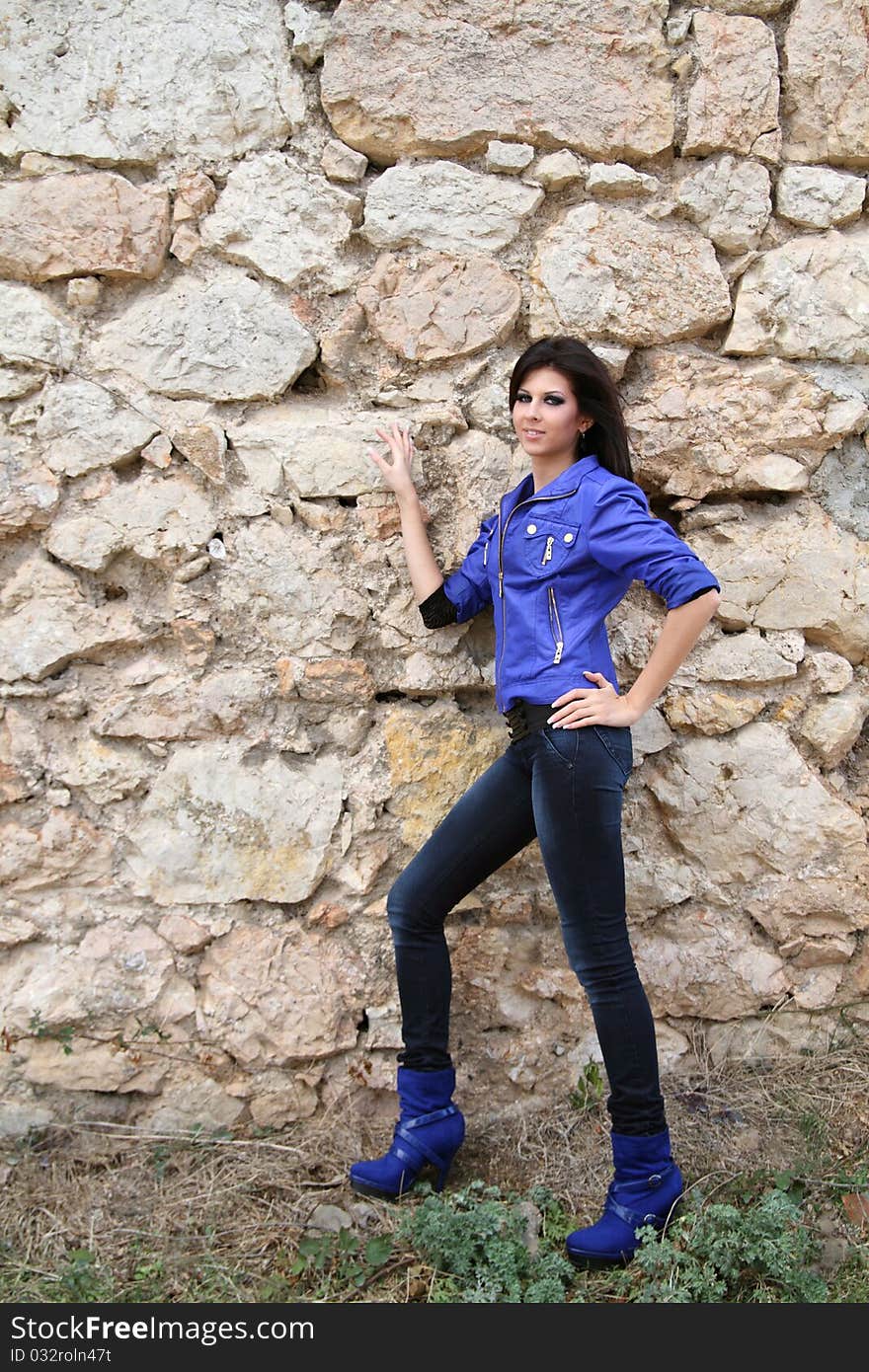 Attractive young girl standing near the old stone wall. Attractive young girl standing near the old stone wall