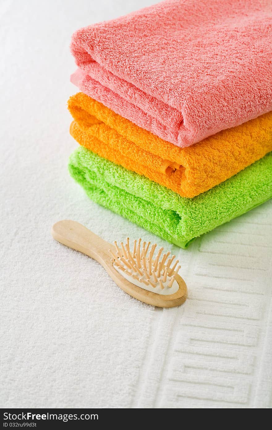 Stack of three cotton towels with hairbrush on white cotton towel