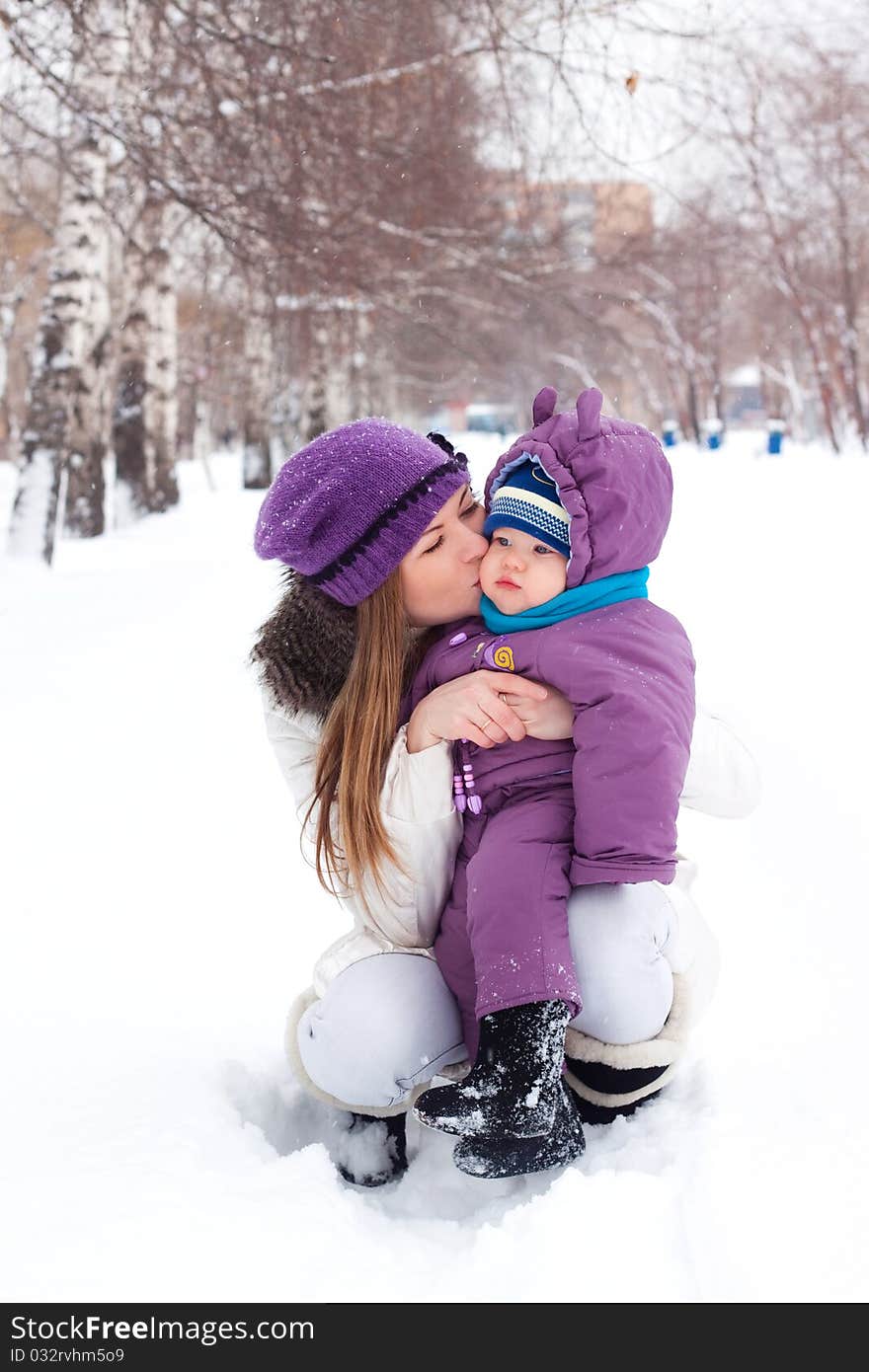 Mother kissing and holding a baby, winter